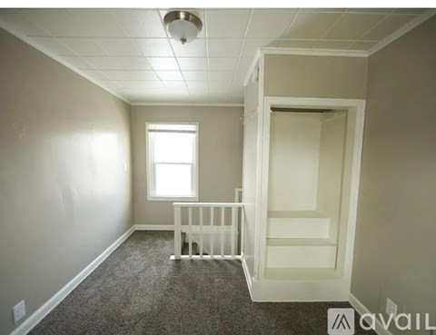 A baby crib sits in a corner of a room with a window.