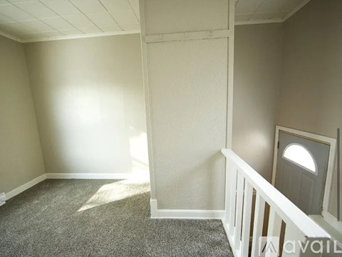 A room with a carpeted floor and a window with a white frame.