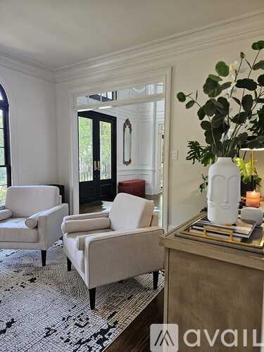 A living room with a sofa, chair, and a table with a vase of greenery on it.