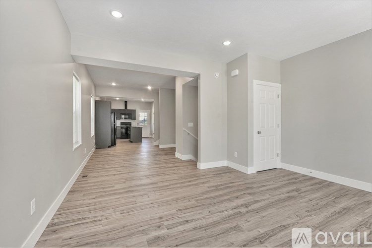A spacious room with wooden flooring and white walls.