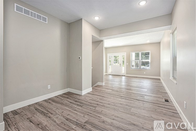 A spacious room with wooden flooring and a window.
