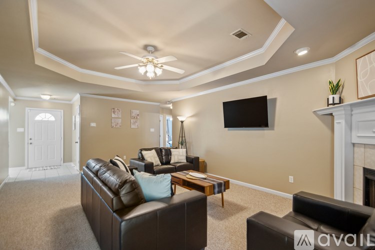 A living room with a brown leather couch and a flat screen TV mounted on the wall.