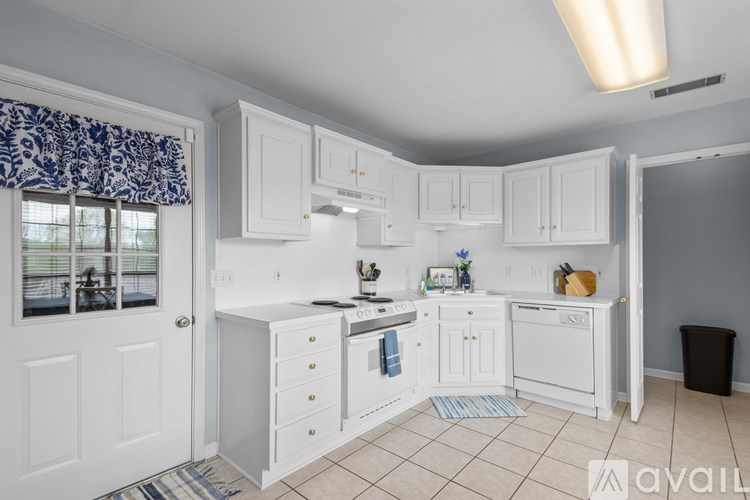 A kitchen with white cabinets and a window with a blue curtain.