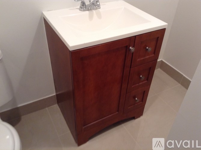 A bathroom vanity with a white countertop and a wooden cabinet.