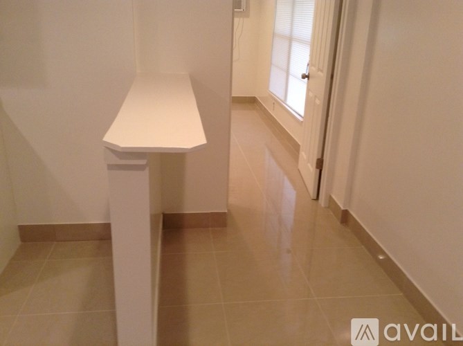 A white lamp stands on a white pedestal in a hallway.