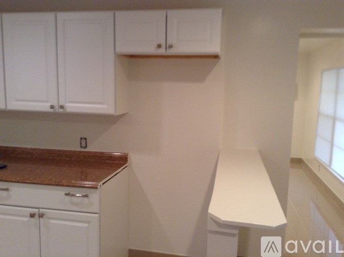 A kitchen with white cabinets and a brown countertop.