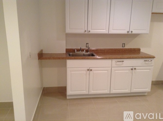 A kitchen with white cabinets and a brown countertop.