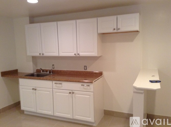 A kitchen with white cabinets and a brown countertop.