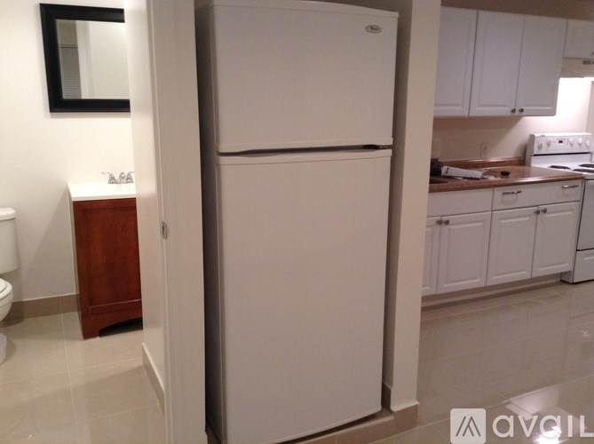 A white refrigerator in a kitchen with white cabinets.