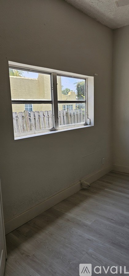 A room with a window, a wall socket, and a wall-mounted air conditioner unit.