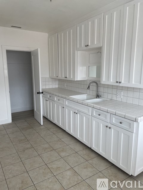 A kitchen with white cabinets and a sink.