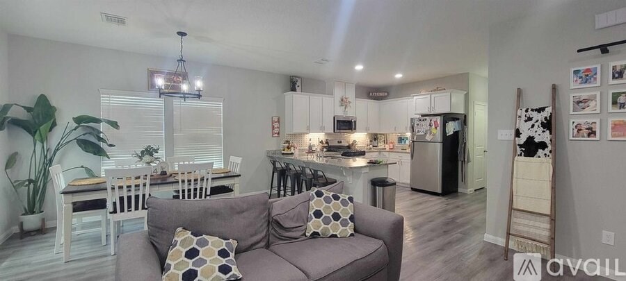 A living room with a grey couch and a dining table with chairs.