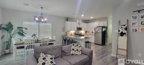 A living room with a grey couch and a dining table with chairs.