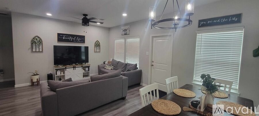 A living room with a grey couch, a television, and a chandelier.