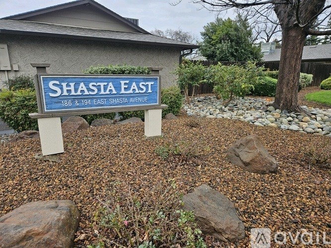 A blue and white sign that says Shasta East stands in front of a house.