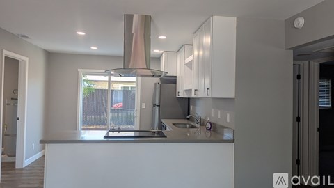 A modern kitchen with a stainless steel range hood and a window overlooking a backyard.