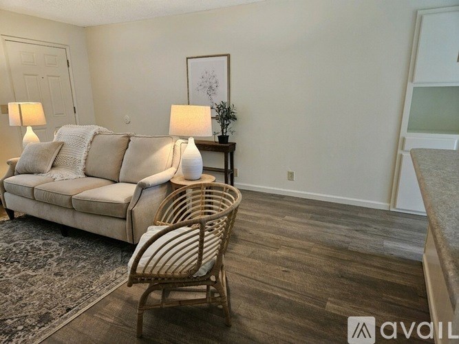 A living room with a beige couch, a wooden chair, and two lamps.