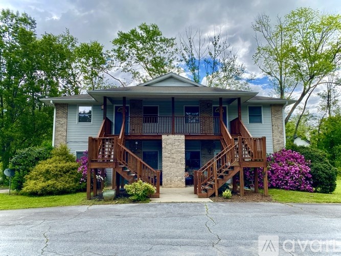 A two-story house with a front porch and stairs leading to the entrance.