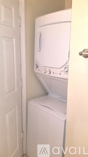 A white washing machine is in a small space between a door and a wall.
