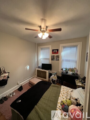 A bedroom with a bed, a ceiling fan, and a window.