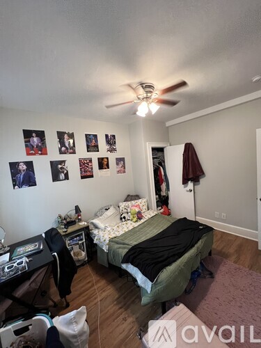 A bedroom with a bed, a desk, and a ceiling fan.