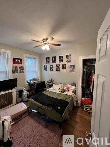 A bedroom with a bed, a TV, a ceiling fan, and pictures on the wall.