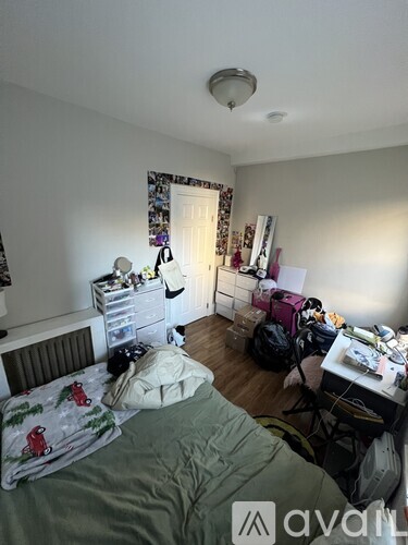 A bedroom with a bed, desk, and a window with curtains.