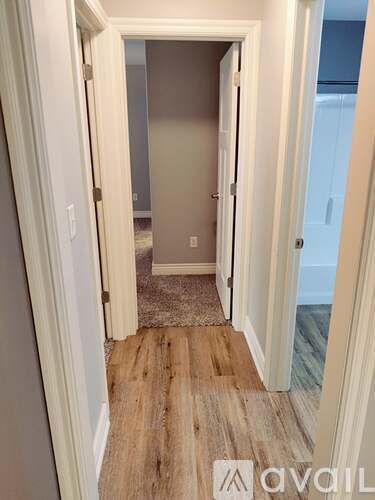 A hallway with a wooden floor and white walls.