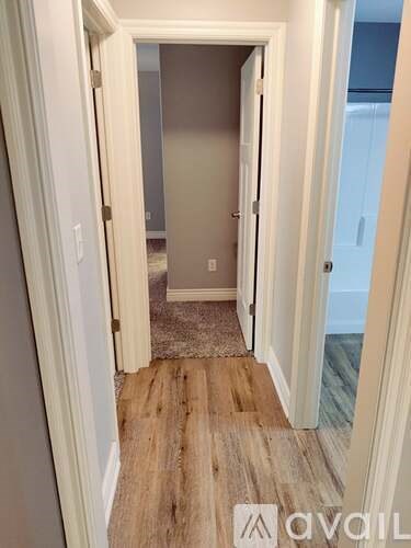 A hallway with a wooden floor and white walls.