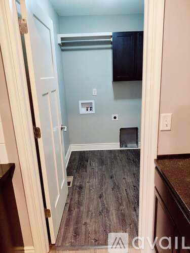 A hallway with a wooden floor and a white door.
