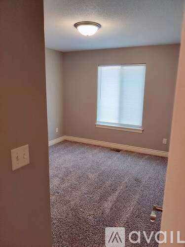 A room with a carpeted floor and a window with blinds.