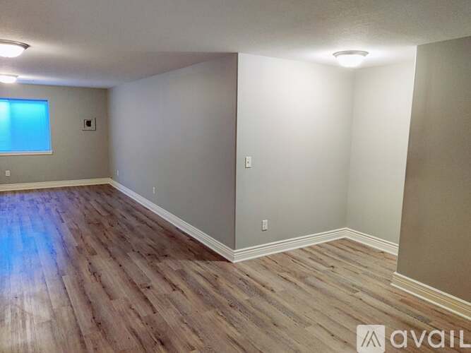 A room with wooden flooring and a window on the left side.