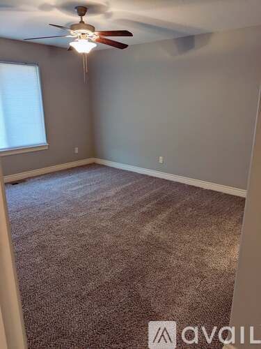 A room with a carpeted floor and a ceiling fan.