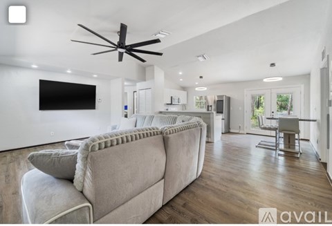 A modern living room with a large couch and a flat screen TV mounted on the wall.