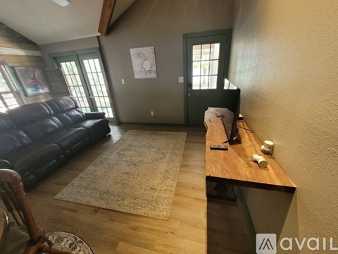 A living room with a black leather couch and a wooden table.