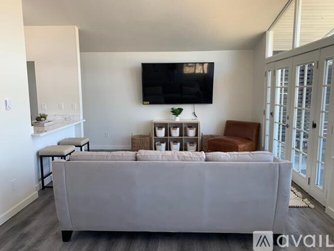 A living room with a grey couch and a flat screen TV mounted on the wall.