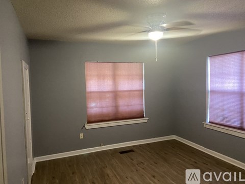 A room with a ceiling fan and two windows with blinds.
