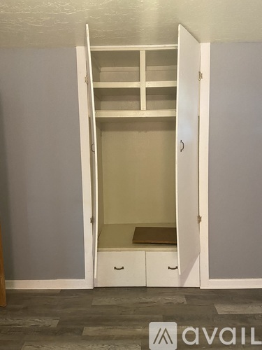 A white wardrobe with a shelf and drawers is open.