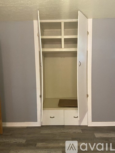 A white wardrobe with a shelf and drawers is open.
