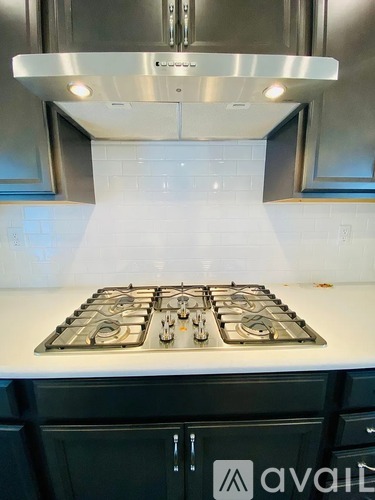 A modern kitchen with a white countertop and a stove top with four burners.