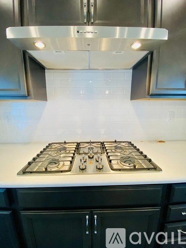 A modern kitchen with a white countertop and a stove top with four burners.
