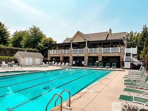 A large swimming pool with lounge chairs and a building in the background.
