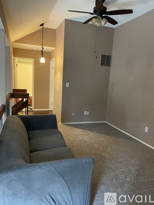 A living room with a grey couch and a ceiling fan.
