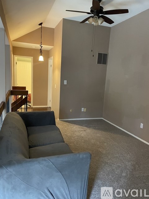 A living room with a grey couch and a ceiling fan.