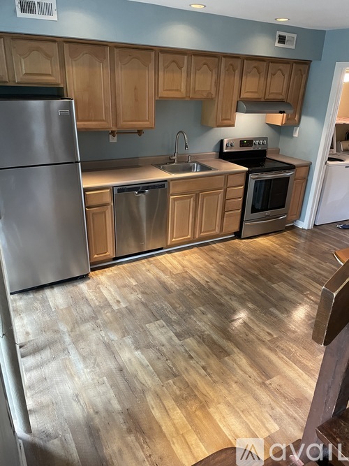 A kitchen with wooden cabinets and a stainless steel refrigerator.