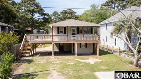 A house with a deck and a tree in front.