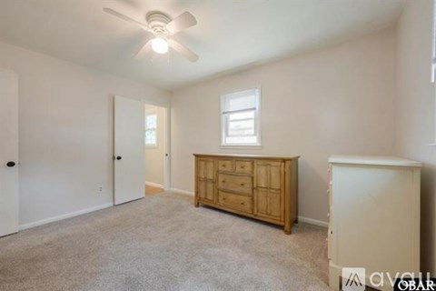 A room with a ceiling fan and a wooden dresser.