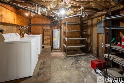 A dirty basement with a white refrigerator and a red toolbox.