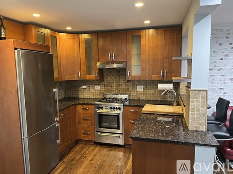 A kitchen with wooden cabinets and a stainless steel refrigerator.