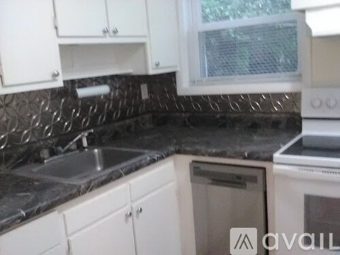 A kitchen with white cabinets and a black countertop.